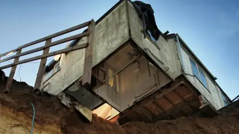 Martin Barber/BBC A picture from 2013 of Bryony Nierop-Reading's home hanging over the top of a cliff edge. 