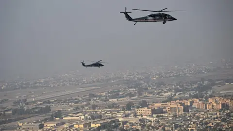 An aerial shot above the city with two helicopters in the air above it