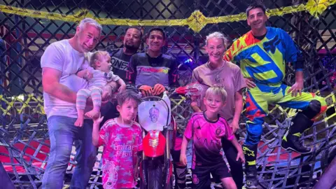 Charles The family are pictured in a large metal ball with performers wearing motorbike clothing. One member of the circus is sat on a dirt bike. 