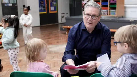 Getty Images UK prime minister Sir Keir Starmer sits with two children 