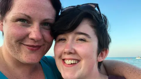Sara Canning Sara Canning. left and Lyra McKee, right, pose for a selfie. They are close to the camera and the sea is in the background.