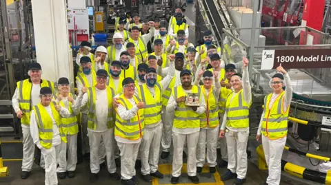 JDE Peet's JDE Peet's employees in the Banbury factory in their hi-vis jackets, hair nets and whit clothing al smiling to the camera.