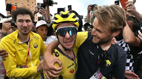 Simon Yates is hugged by a member of the Visma-Lease A Bike team staff after taking the lead in the 2025 Giro d'Italia