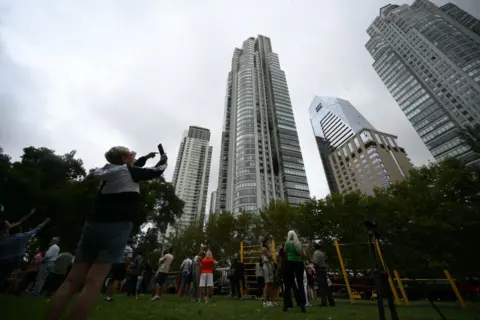 Getty Images People look at a skyscraper after dozens of people were evacuated from the 50-story apartment building that caught fire at Puerto Madero in Buenos Aires on 11 February 2025