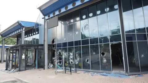 pacemaker The outside of Larne Leisure Centre showing many windows broken or shattered and glass on the ground