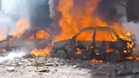 A screengrab from social media video shows vehicles on fire in Tehran 