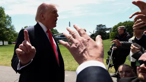 Trump talking to reporters whil holding finger up to camera