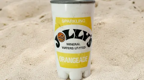 Jolly's Drinks A tin of soft drink in black, yellow and white with words on the front.