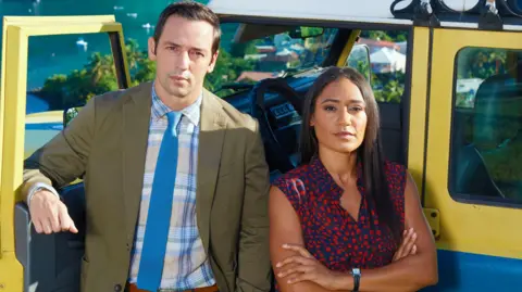 Red Planet Ralph Little and Josephine Jobert. A man wearing a suit and a woman wearing a dress standing crossed arms in front of a car. 