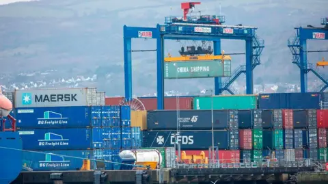 Image of multiple shipping containers at Belfast Harbour. Coloured in blue, green, yellow, red and silver. 