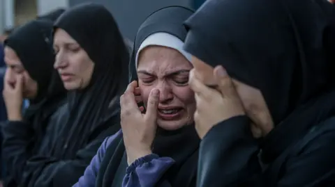 EPA Palestinian women mourn members of a family killed in an Israeli airstrike at Al Aqsa Martyrs Hospital in Deir Al Balah town, central Gaza Strip, on 15 January 2024.