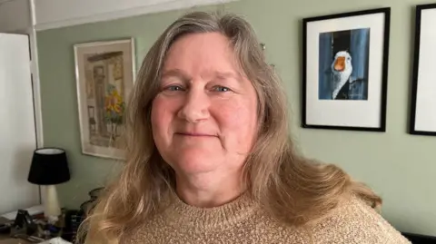 Julie Dickson stands in her living room on Holness Road, Ash