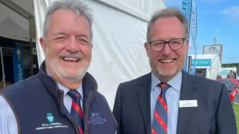 Chris Riddle (left) and Mark Stoddart, who is taking over the role. The pair are standing next to one another and smiling at the camera.