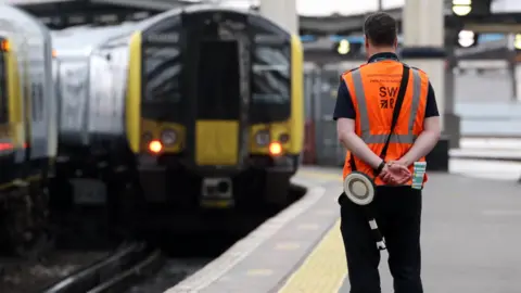 EPA A waterloo station worker watches as a train approaches a platform