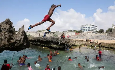 Feisal Omar / Reuters A boys jumps through the air into the sea where other children are swimming in Mogadishu, Somalia - Thursday 6 November 2025. 