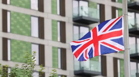 Reuters A union jack flag hangs from a lamp post next to a residential building. It is attached with black cable ties. 