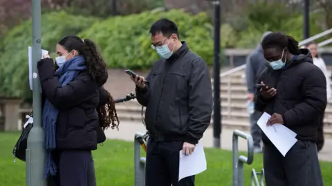 Three people standing in a queue. 