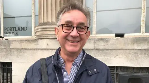 Mick Antoniw smiling for a picture, taken outside Portland House in Cardiff Bay