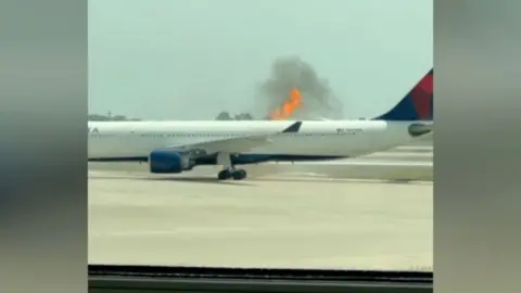 The back end of a Delta plane with flames coming out of the top