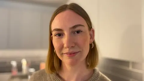 Jessica Salgado, a woman with short ginger hair, standing in her kitchen