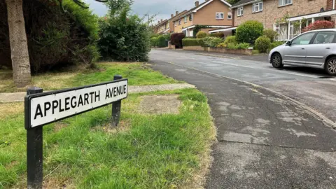 LDRS The entrance to Applegarth Avenue with the road sign and semi-detached houses in the background