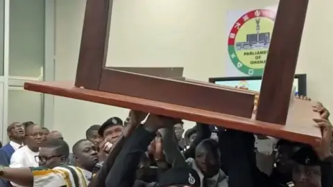 A group of MPs lift a wooden tables above their heads