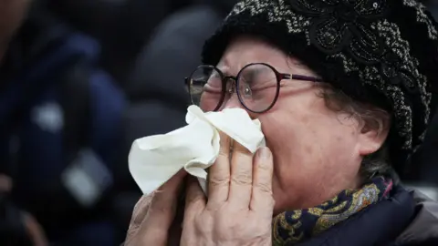 Reuters A relative of a passenger of the aircraft that crashed after it went off the runway, tearfully blows her nose. 