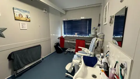 A bathroom that has been specially adapted for Sam and Alex. There is a sink and specialist equipment around the room.