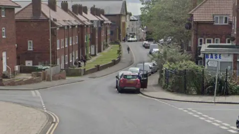 A screengrab of Google Maps Street View, showing a junction of four primarily residential streets.