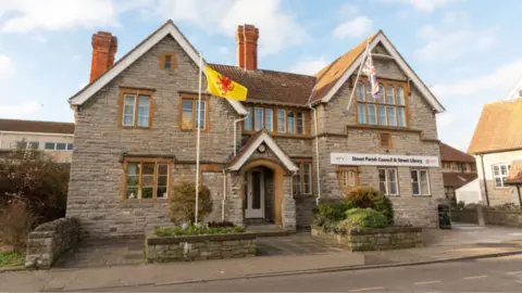 Somerset Council A brick building with a sign which says "Street Parish Council and Street Library" with a yellow flag outside.