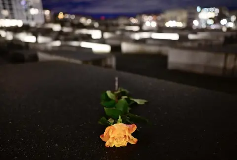 JOHN MACDOUGALL/AFP A yellow rose on a memorial stele at The Memorial to the Murdered Jews of Europe, also known as the Holocaust Memorial, in Berlin, on January 27, 2025.