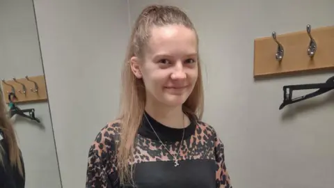 Family handout A girl with long blonde hair and a leopard-print top smiling at the camera