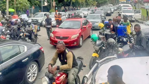 BBC Cars and motorbikes queuing for fuel in Lagos, Nigeria - September 2024