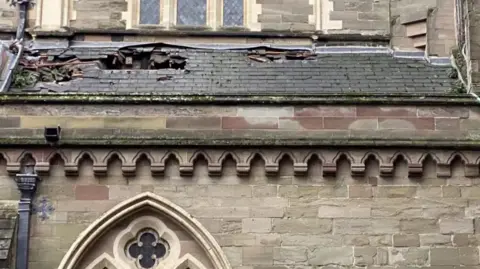@BISHOPWORCESTER Three large holes are seen in the roof of the cathedral. Tiles have been ripped away and are bent inwards.