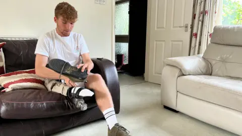 Ollie sitting on a sofa and putting his blade on