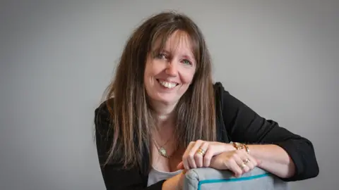 Samantha Everard sitting on a chair looking towards the camera with her arms folded.