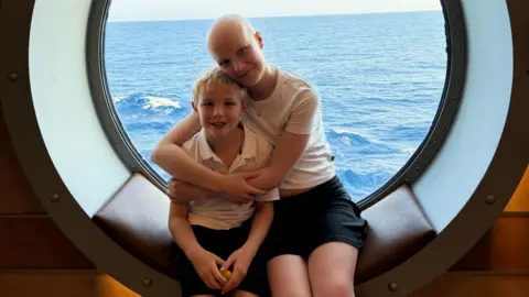 Vicky Robayna/PA Wire Liz hugging her brother Mateo as they sit in the window of a boat with the sea in the background. 