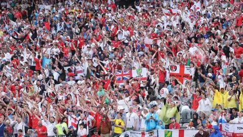 Getty Images A large crowd of people holding flags of St George and Union Jack. 