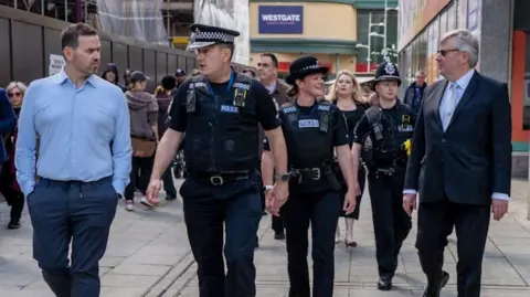 Essex Police Ben-Julian Harrington walking with other police officers and people in a busy town centre street in Basildon.