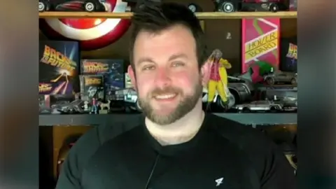 Pacemaker A man with dark spiky hair and a tight black t shirt 