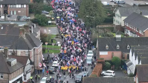 Eddie Mitchell A group of protesters with Union Jack flags marching through a town.