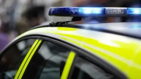 A generic picture of a police car with blue lights on its roof illuminated.