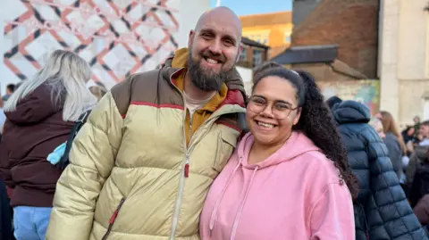 Danny Fullbrook/BBC A couple smile together on an outdoor town centre street