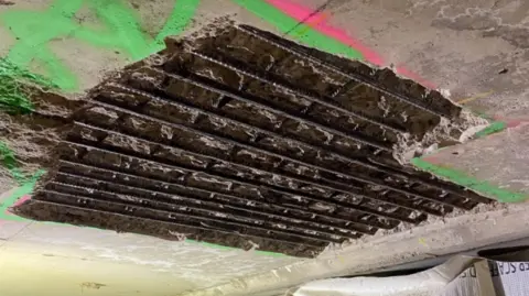 A photograph of the exposed metal bars on the underside of the bridge. 