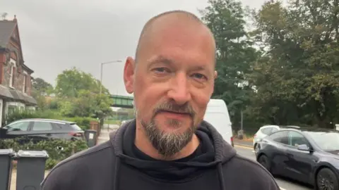 BBC A man with a beard wearing a black hoodie 