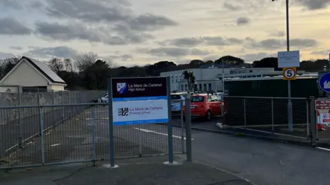 A picture of the sign outside La Mare De Carteret High School at twilight.