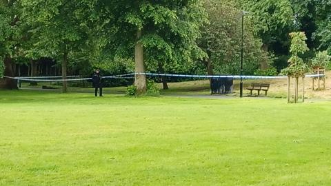 Police officer in park next to a cordon