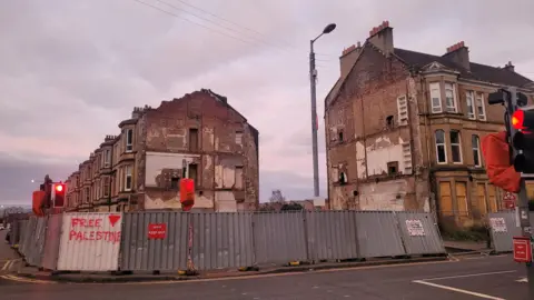 Derelict buildings in Pollokshields, with boarding around it 