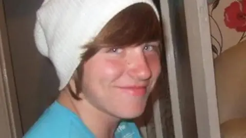 Family photograph Dylan Ramsay wearing a white woolly slouchy hat and turquoise top.