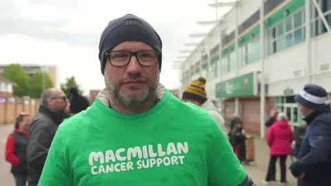 Stephen Huntley/BBC Mike Adams in a green MacMillan cancer support t shirt